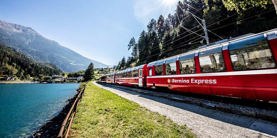 The Bernina Express travels past a shimmering blue lake.  